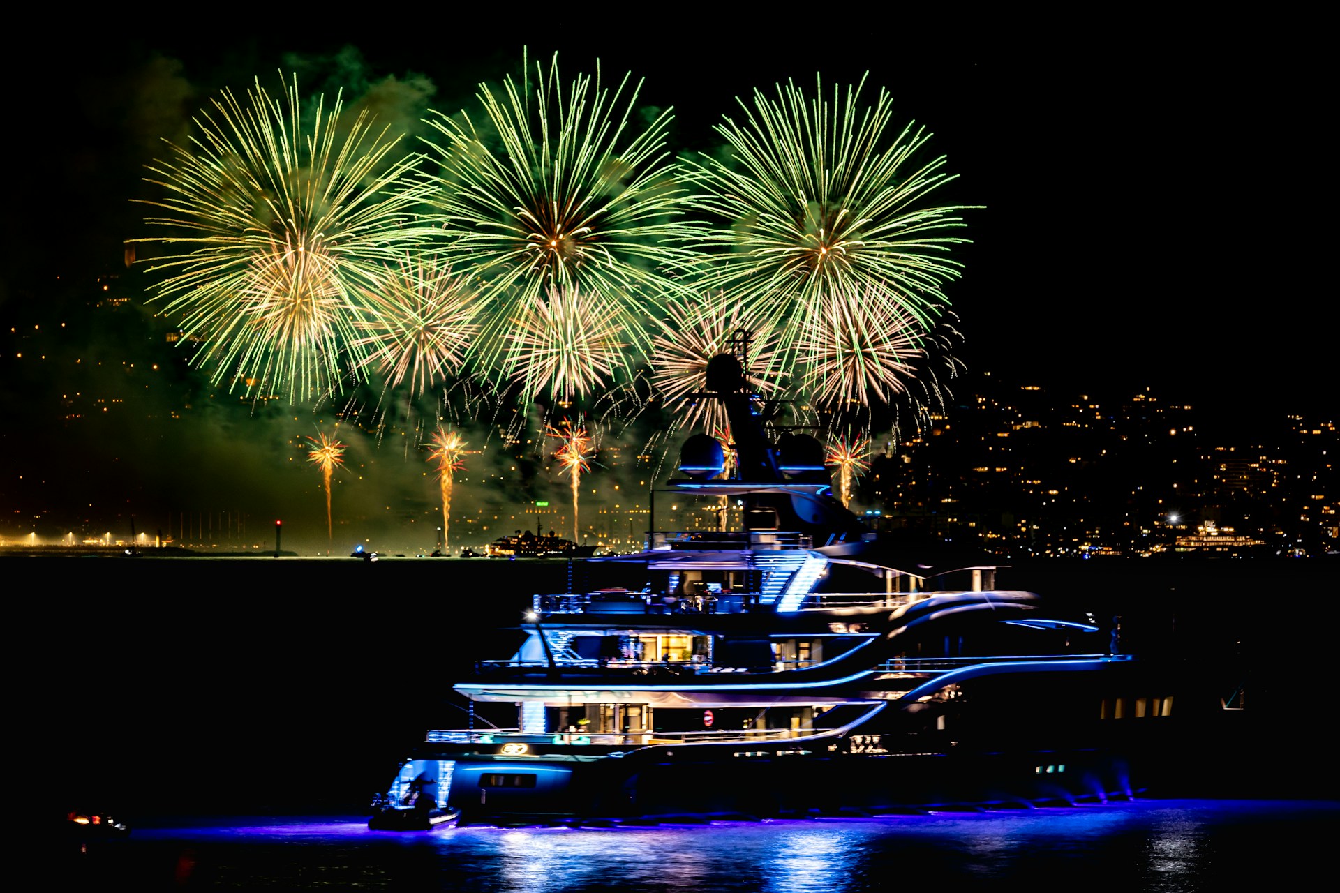 Illuminated superyacht in front of green fireworks on the French Riviera